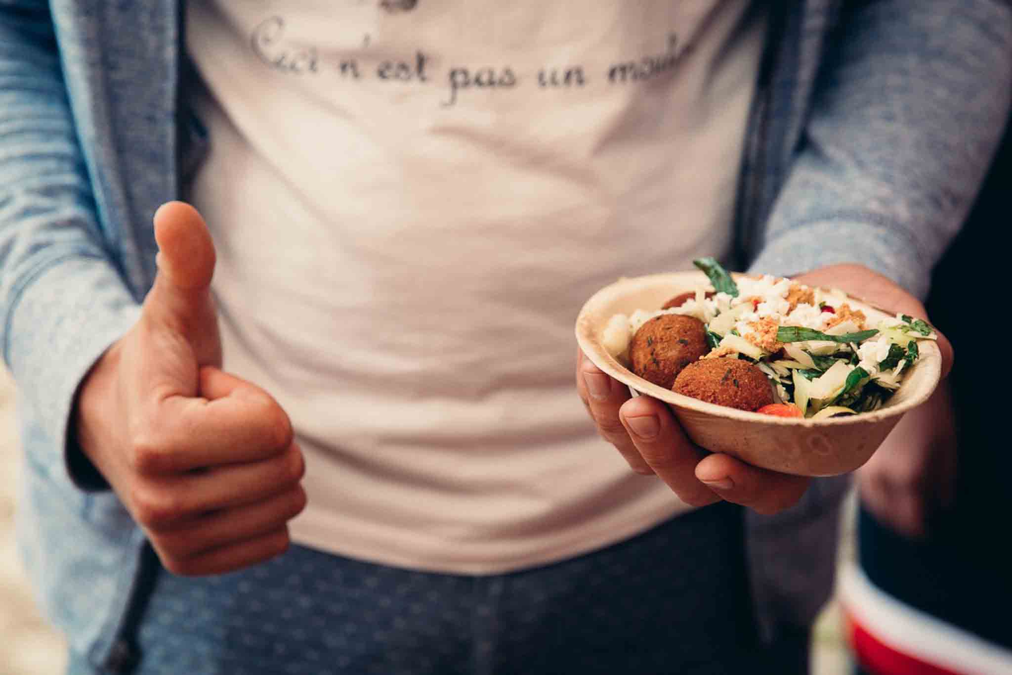 Man houdt falafel in kommetje vast en steekt duim omhoog.