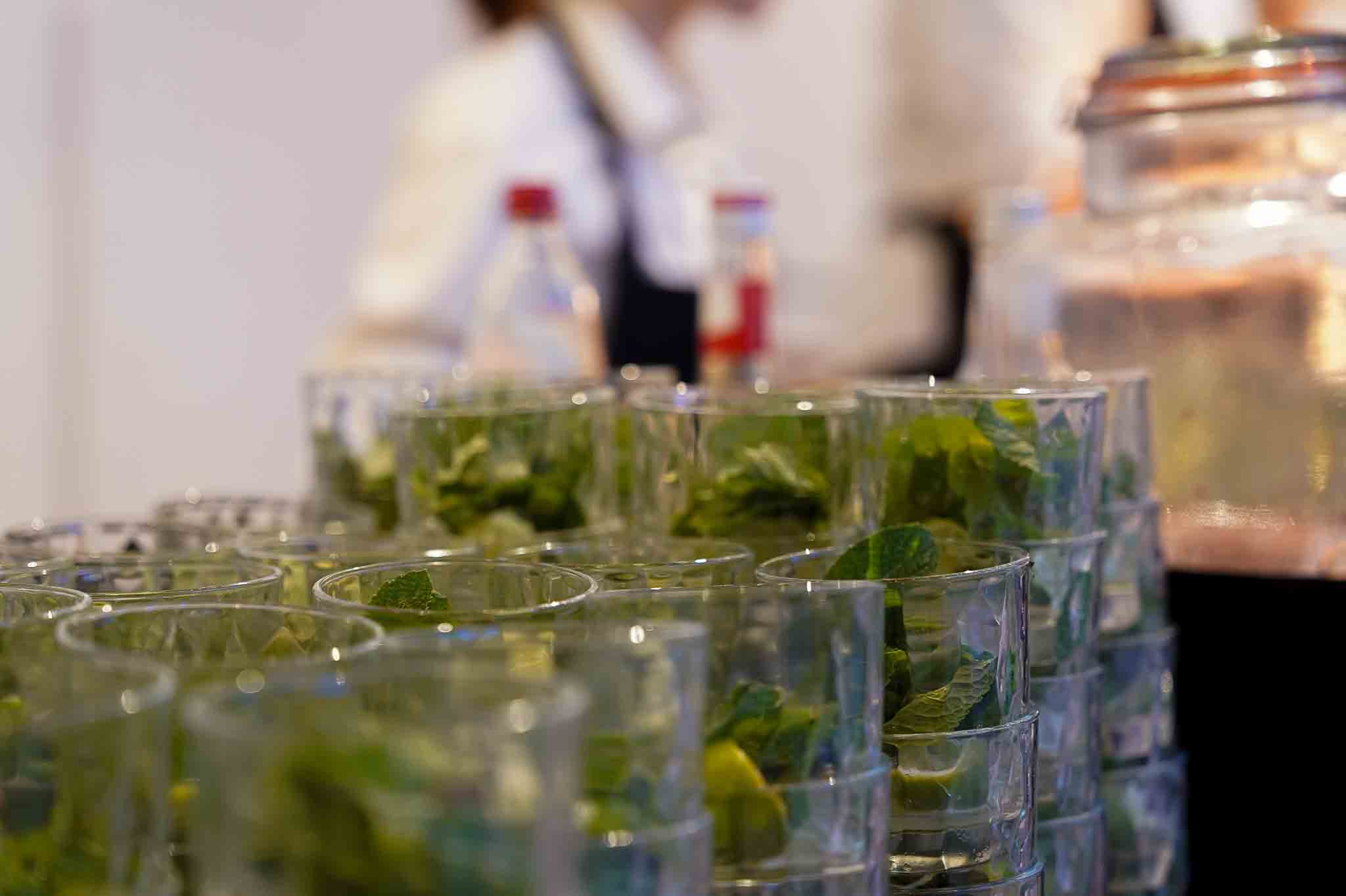 Mojito cocktails op de voorgrond met daarachter een werkneemster die ze aan het maken is.