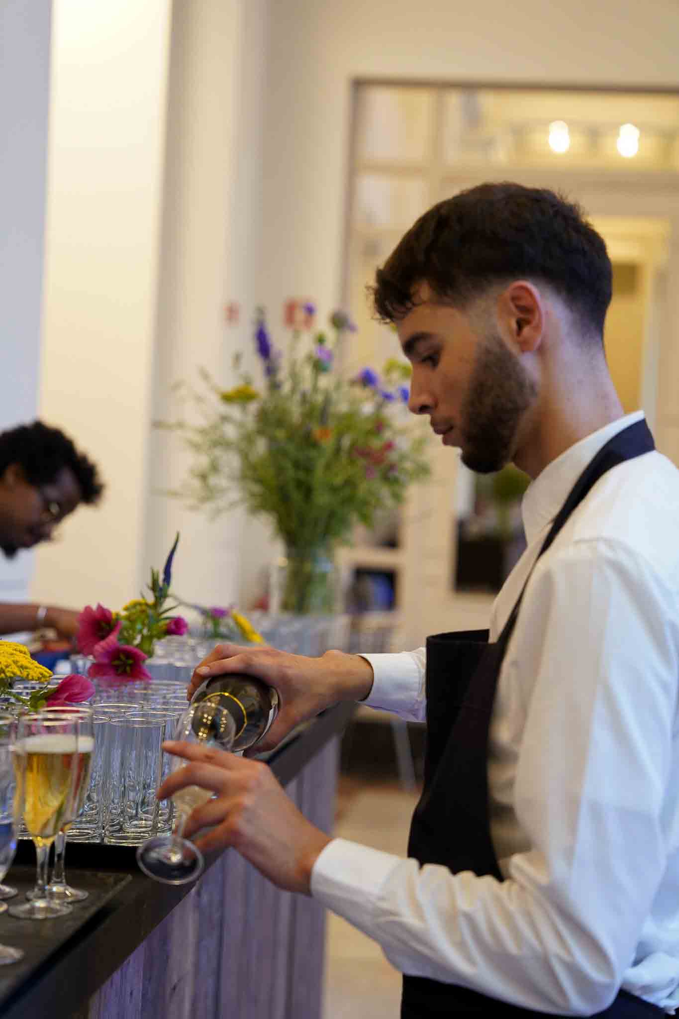 Een medewerker schenkt champagne in.