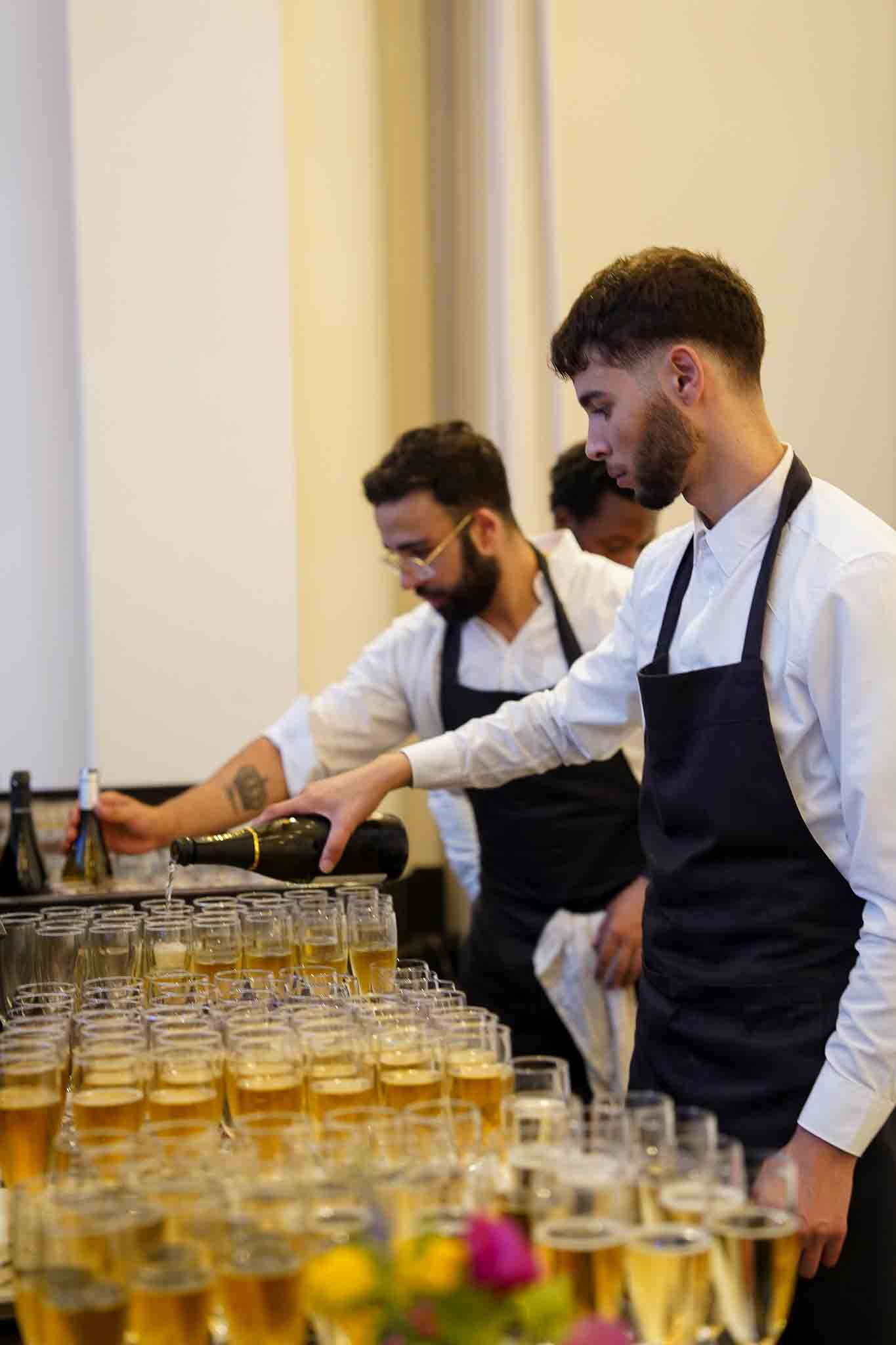 Meerdere medewerkers gieten champagne in.